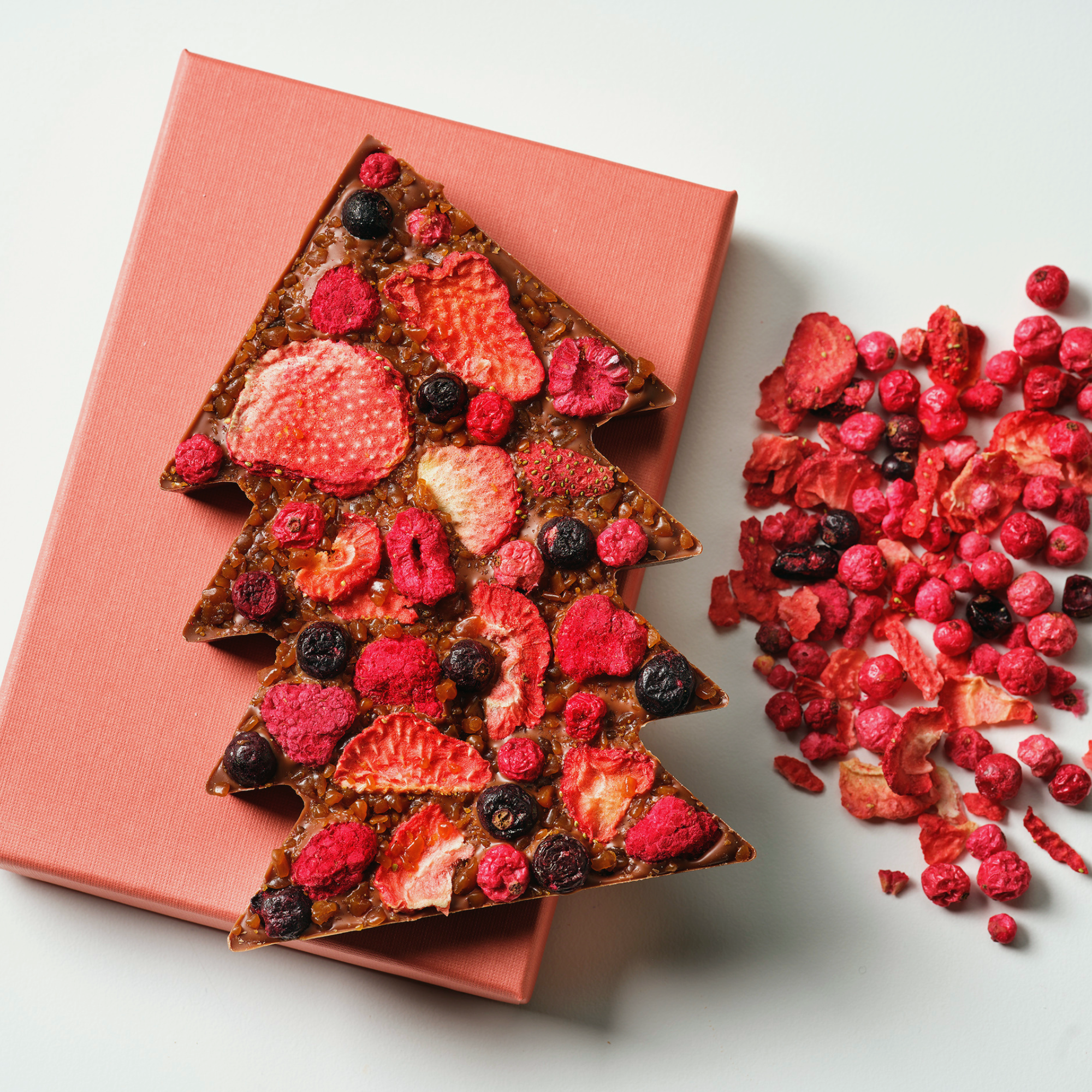 Fruit and nut bar shaped like a Christmas tree with berries on a pink box.